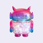 Pink and purple ombre soft vinyl figure with iridescent tinsel inside its body. Figure is shaped like a smaller Big Boss Robot, with a bigger head than normal and two black eyes with sparkles as pupils. A red heart is on its upper right chest.