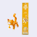 Paper sculpture of an orange tabby cat, made out of folded paper pipes. It stands next to its orange product packaging.