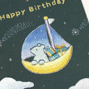 Embroidered design of a polar bear on a crescent moon with presents, sailing on a starry night sky.