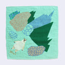 Teal green square towel with illustrations of stylized pointy green and blue mountains, with rocks. A fluffy cream colored polar bear stands at the bottom.