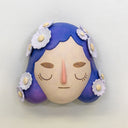 Sculpture of a person's head with a solemn yet sweet expression. They have mid length purple hair with white flowers all over like hair pins.