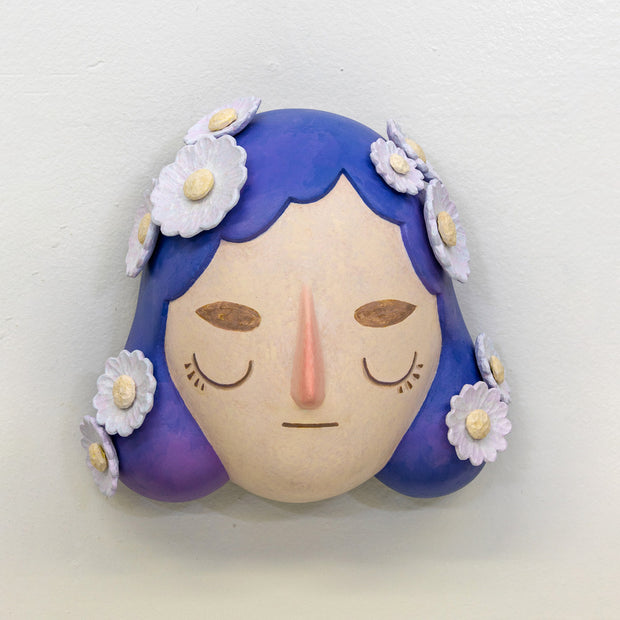 Sculpture of a person's head with a solemn yet sweet expression. They have mid length purple hair with white flowers all over like hair pins.