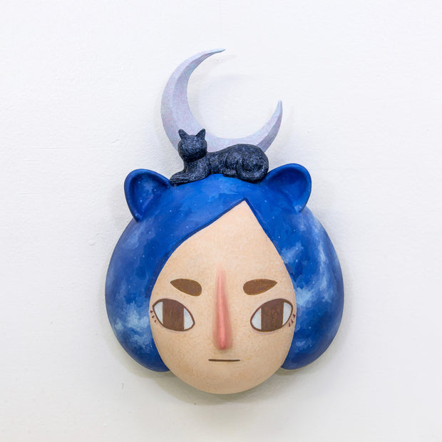 Sculpture of a person's head with a solemn yet sweet expression. They have mid length blue galactic pattern hair and small animal ears. A cat and a purple crescent moon sit atop their head.