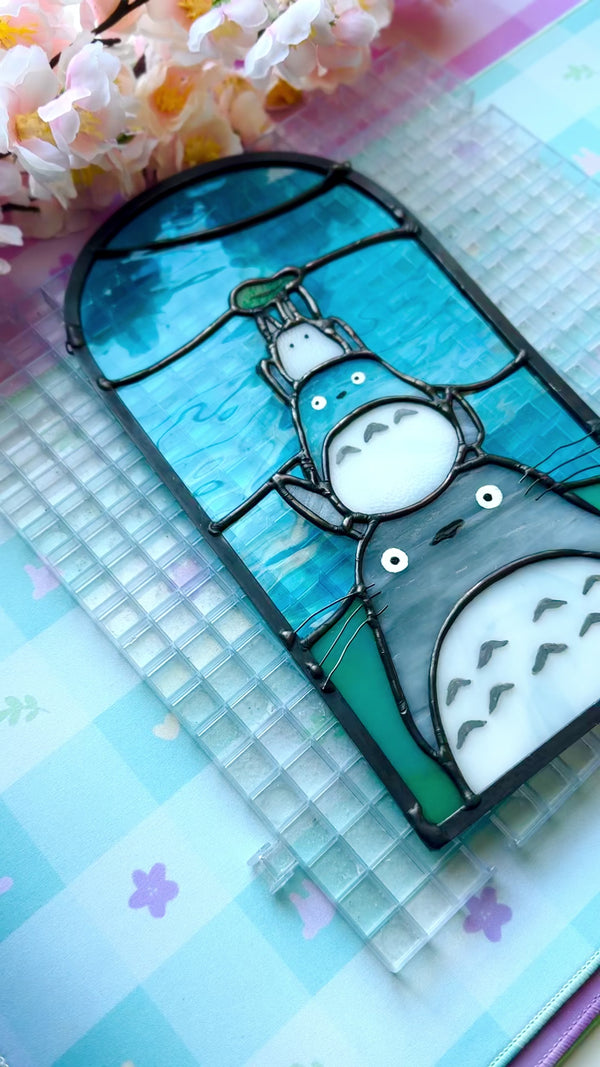Stained glass panel with Totoro characters from Studio Ghibli, stacked atop of one another.