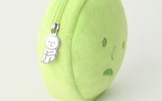Close up of silver zipper accessory on a round plush pouch shaped like Smiski's head. The zipper is of Smiski sitting with their knees pulled into their chest.