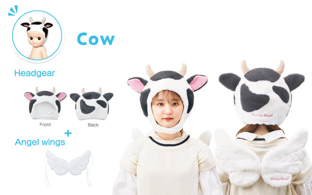 Photo display of the Sonny Angel Cow costume, a white fluffy cow shaped hood hat with black spots, pink inner ears and small horns. Includes a matching set of white wings. A girl models the hat and wings.