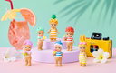 Toy figures in summer attire with a colorful drink and camera on a pastel background