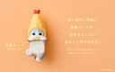 Figurine of a gray cat with a tempura shrimp hat atop of it and a flat belly that has an adhesive strip - allowing it to be stuck to items.