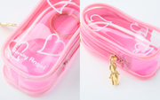 Close up photo of a pink clear plastic case, oval in shape, with white heart illustrations on the exterior. It has a small gold Sonny Angel shaped pennant on the side.