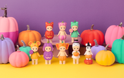 Colorful pumpkins and figurines on a yellow surface with a purple background