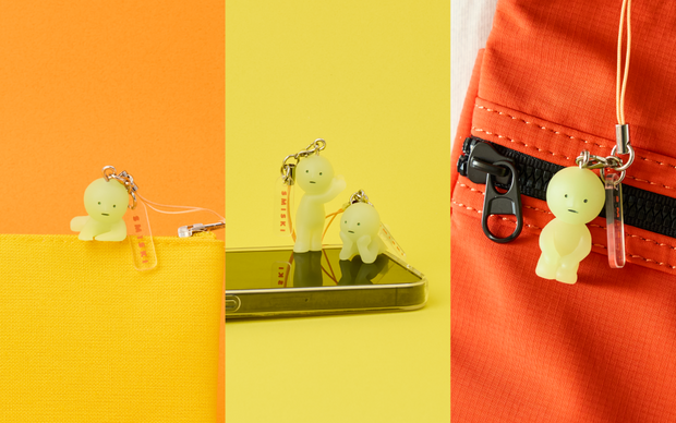 Small Smiski keychain figures, doing various poses and attached to different items such a zippers, cell phones, bags.