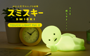 Smiski touch light with a clock and plant on a wooden surface