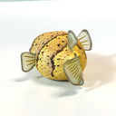 Clay sculpture of a yellow and brown puffer fish, with semi transparent fins and large black eyes. 