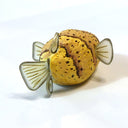 Clay sculpture of a yellow and brown puffer fish, with semi transparent fins and large black eyes. 