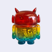 Rainbow colored soft vinyl figure with a black line art drawing inside its body, with mechanical imagery. Figure is shaped like a smaller Big Boss Robot, with a bigger head than normal and two black eyes with sparkles as pupils. A red heart is on its upper right chest. Back view.