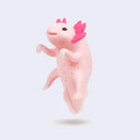 Pink silicone tea infuser shaped like an axolotl with a smiling face, Its hands hang over the rim of the cup to keep itself up and tea diffuses from small holes in its body.
