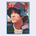 A vintage magazine or book cover titled "Reminiscence of Bruce Lee" with a large portrait of Bruce Lee wearing a blue hat, surrounded by colorful text and a purple callout sticker, photographed against a light gray background.