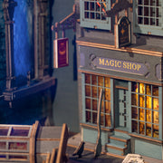 Close up image of Magic House diorama bookend kit, fully assembled to display the exterior of a magic shop with European style street signs and a bird and broom perched outside.