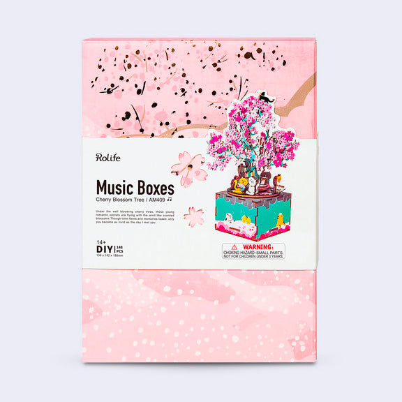 Product packaging for a music box kit, designed to look like a 3D cherry blossom tree with cats sitting on and around it.