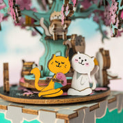Close up detail photo of 2 cats, made out of wood and puzzled together, sitting under a tree.