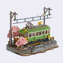 Model of a green train with cherry blossom trees on a white background