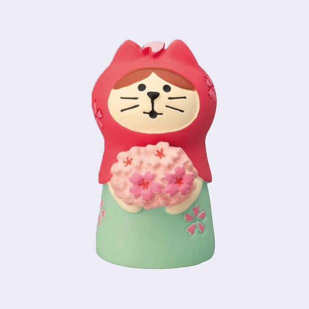 Small resin figure of a cat with a pink hood and mint dress holding a bouquet of cherry blossoms