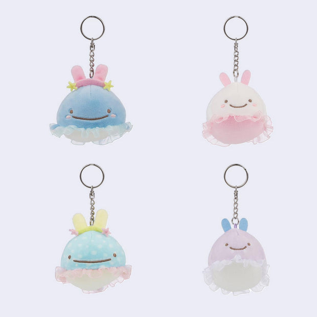 Four pastel-colored plush keychains with rabbit ears on a light purple background