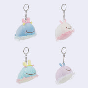 Four plush whale keychains with different colors on a light purple background