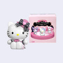 Hello Kitty figurine with a pink bow next to a display box featuring more Hello Kitty figures.