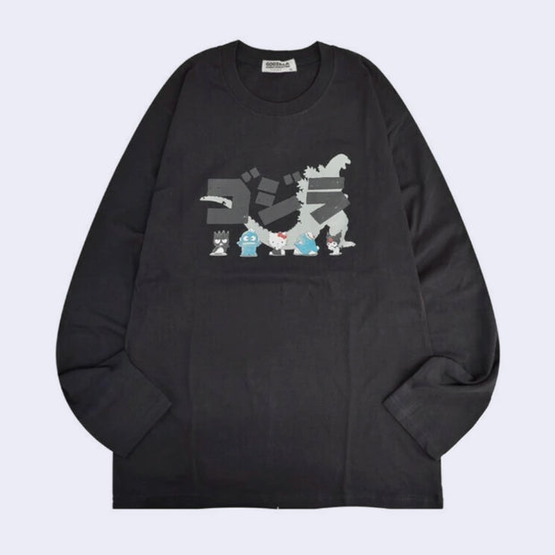 Dark gray long sleeve shirt with a silhouette of Godzilla with Japanese kanji atop of it. In front of Godzilla stand 5 Sanrio characters, very small in comparison: Badtz-Maru, Hangyodon, Hello Kitty, Tuxedo Sam and Kuromi.