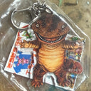 Dinosaur-shaped keychain with packaging on a textured surface