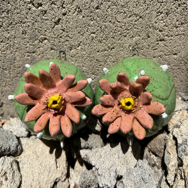 Ceramic sculpture of a pair of peyote cacti, with small white spikes and large blossomed pink flowers in the center.