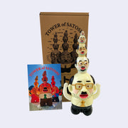 Glow in the dark colored vinyl figure of a short, stout business man. Atop his head are 4 other heads similar to his own, each one smaller then the next, building a tower of sorts. It stands in front of its product packaging.