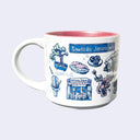 White ceramic mug with a metallic pink interior and various illustrations on it, all within a color scheme of blue, pink, white and green. Illustrations include a bonsai tree, sashimi, sushi rolls, cherry blossoms, a food stall that says "Ketchie's Stand," a street sign that says "Sawtelle Japantown" and a shaved ice cone.