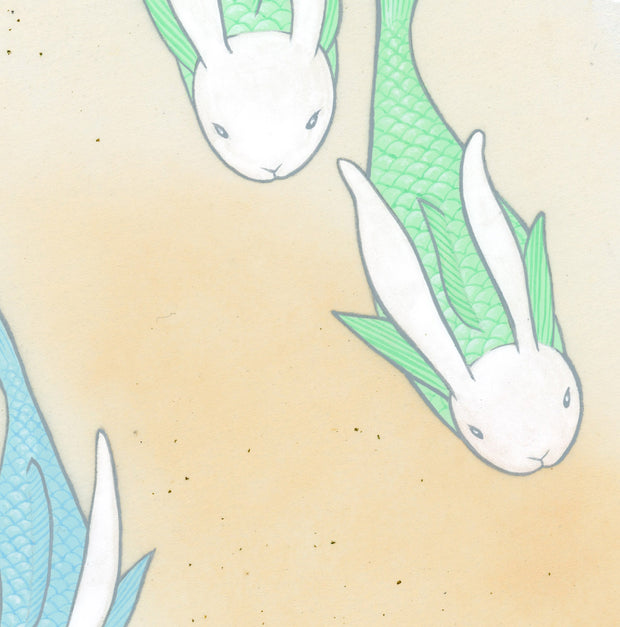 Paper circle with deckled edges and a soft orange and cream colored watercolor background. Blue and green fish with white bunny heads swim calmly. Close up.