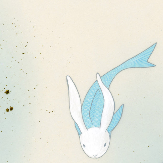 Paper circle with deckled edges and a soft blue and cream colored watercolor background. Blue and green fish with white bunny heads swim calmly. Close up showing bunny faces.