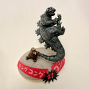 Sculpture of a tiny king kong, throwing around a giant godzilla by his tail on a base with Japanese writing.