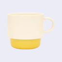 Mug with a yellow bottom and beige top on a light purple background