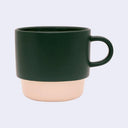 Green and beige ceramic mug on a light gray background