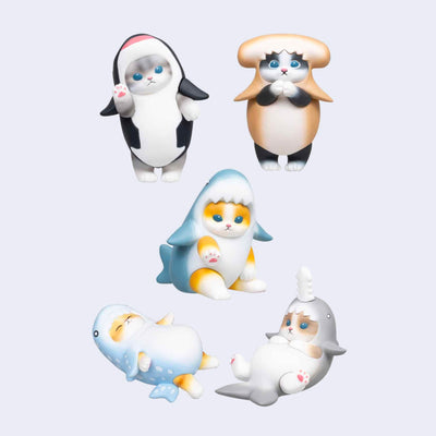 5 small plastic figures of cats, different colorings, all in full body shark costumes of different colors and shapes. 