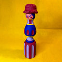 Colorful wooden toy figure with a red hat on a yellow background