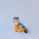 Small ceramic sculpture of an orange and blue-gray fox with carved poppy flower design.