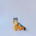 Small ceramic sculpture of an orange and blue-gray fox with carved poppy flower design.
