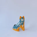 Small ceramic sculpture of an orange and blue-gray fox with carved poppy flower design.