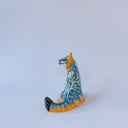 Small ceramic sculpture of an orange and blue-gray fox with carved poppy flower design.