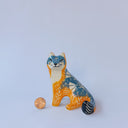 Small ceramic sculpture of an orange and blue-gray fox with carved poppy flower design.