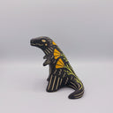 Matte finish ceramic sculpture of a T-Rex dinosaur, black with cream colored sgraffito line detailing and golden poppy flower designs on its back.