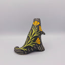 Matte finish ceramic sculpture of a T-Rex dinosaur, black with cream colored sgraffito line detailing and golden poppy flower designs on its back.