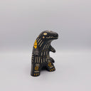 Matte finish ceramic sculpture of a T-Rex dinosaur, black with cream colored sgraffito line detailing and golden poppy flower designs on its back.