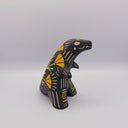 Matte finish ceramic sculpture of a T-Rex dinosaur, black with cream colored sgraffito line detailing and golden poppy flower designs on its back.